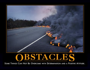 A poster showing a paved road with a huge, long boiling mass of molten lava pouring out across the road, black smoke billowing up from it. Under the picture in large orange letters, it says, "Obstacles." Beneath that in smaller type, it says, "Some things cannot be overcome with determination and a positive attitude."