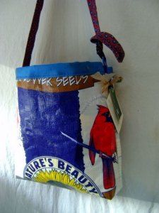 Colorful tote bag made from bird seed bags, includes a bright red cardinal sitting on a branch, and a sunflower at the base of the bag.