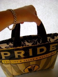 Tote bag in black and yellow that says Pride in big yellow letters on a black background.