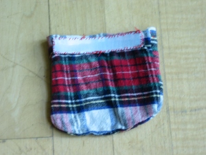 Back of a red plaid flannel pouch with strip of white Velcro sewn across the top.